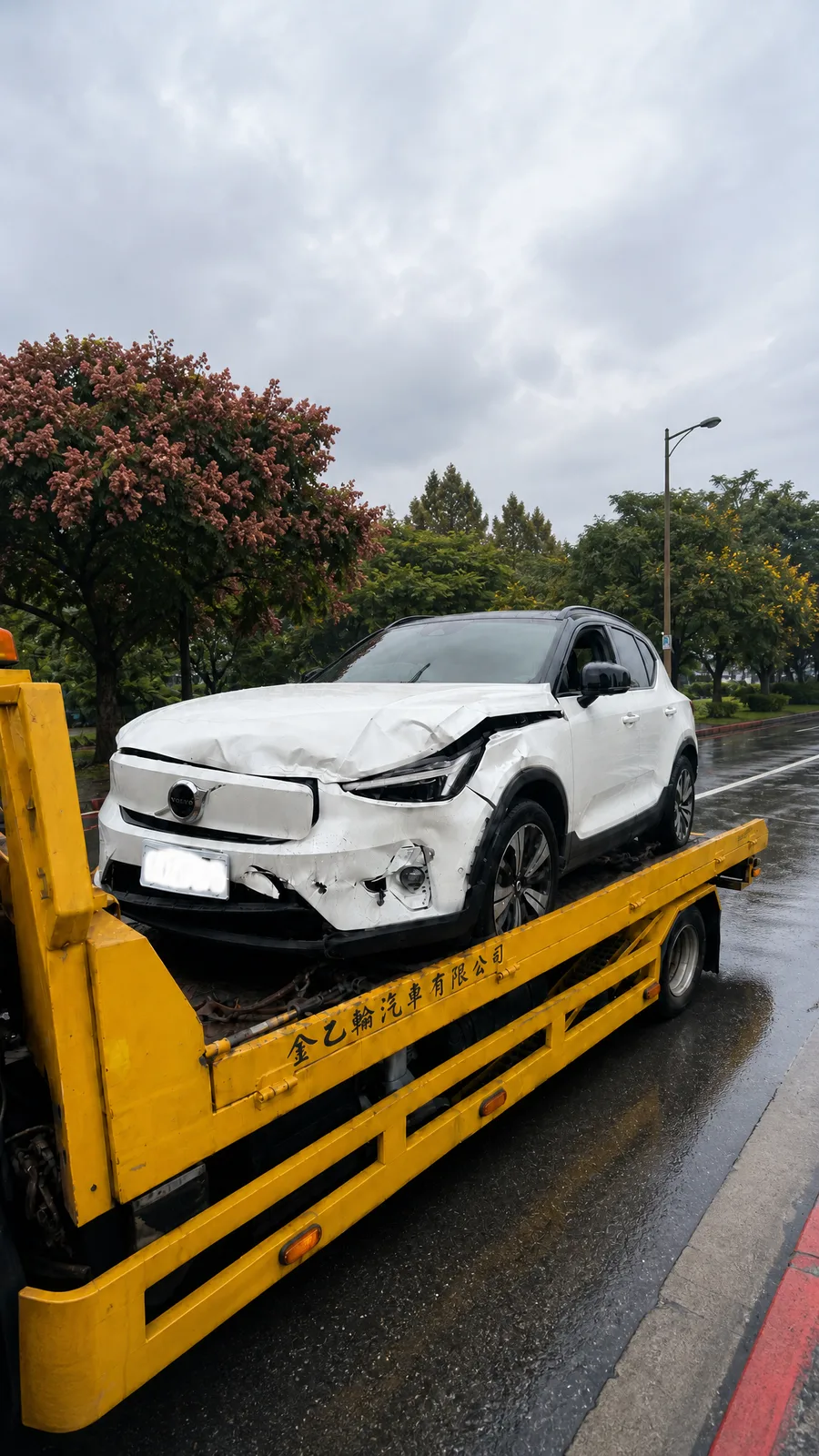 前保桿撞損的白色 Volvo XC40 電動休旅車，停放在平板拖車上準備運送